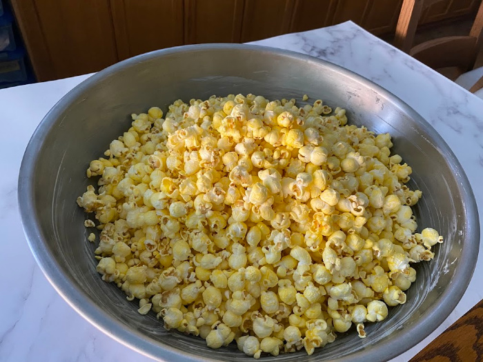 Place popped popcorn in buttered bowl