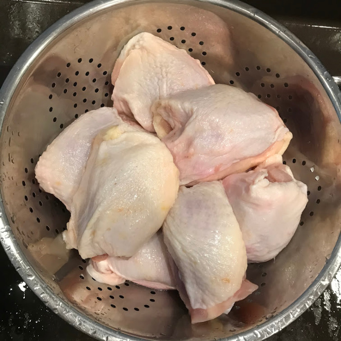 Washing the chicken thighs in a strainer