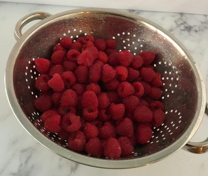 Raspberries being washed in strainer