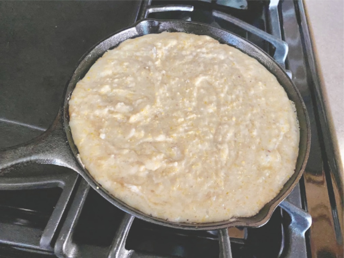 Cornbread batter in hot cast iron pan