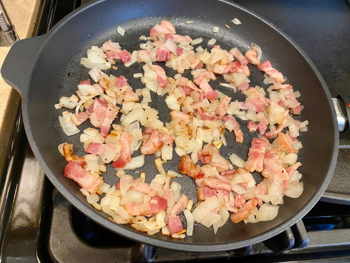 Frying pan with cooked bacon and onions