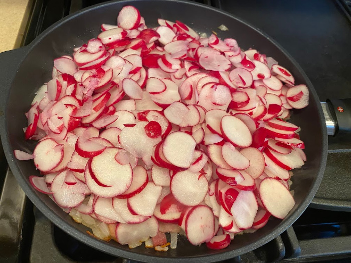 Place the sliced radishes on the fried bacon and onions
