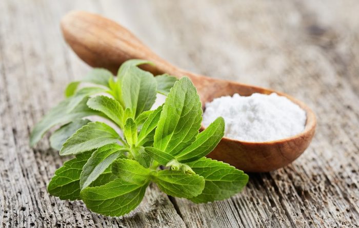 Stevia leaves and powder on wood plank