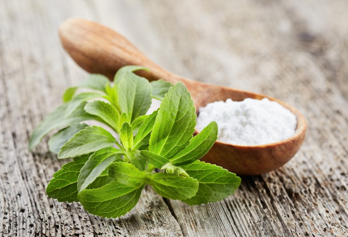 Stevia leaves and powder on wood plank