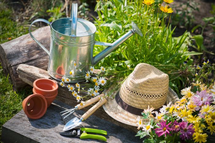 Gardening tools and a straw hat on the grass in the garden