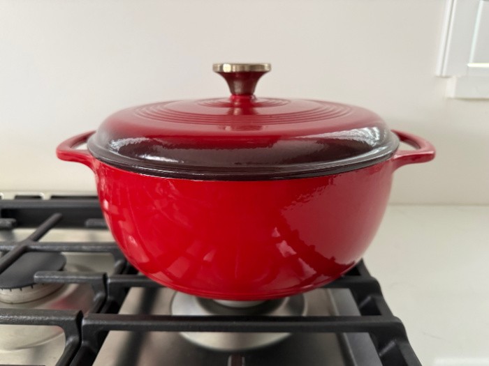 Dutch Oven Red Sitting On The Stove With Lodge Knob