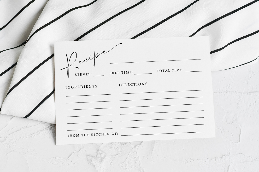 A single blank printable recipe card template featuring a minimalist layout, resting on a black and white striped kitchen towel.