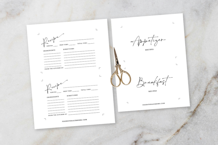 Two sheets of a printable recipe card template and appetizer/breakfast dividers on a marble surface with vintage gold scissors.