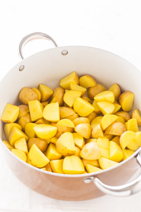 Chopped gold potatoes in a large pot of water, ready to be parboiled for a Crispy Oven Roasted Potatoes Recipe.