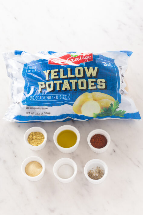 Ingredients for a Crispy Oven Roasted Potatoes Recipe including a 3lb bag of yellow potatoes, olive oil, and spices.