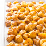 Golden brown and Crispy Oven Roasted Potatoes Recipe spread out on a baking sheet after being baked at 425 degrees.