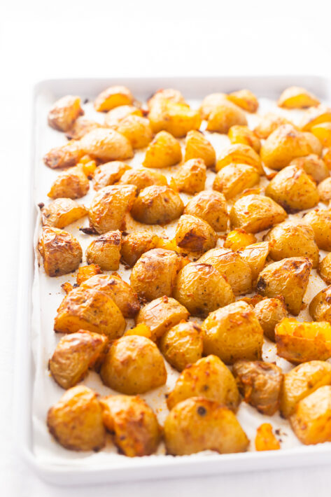 Golden brown and Crispy Oven Roasted Potatoes Recipe spread out on a baking sheet after being baked at 425 degrees.