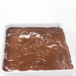 Spread melted peanut chocolate topping, sprinkled with flakey salt, just before freezing the no bake peanut butter bars.