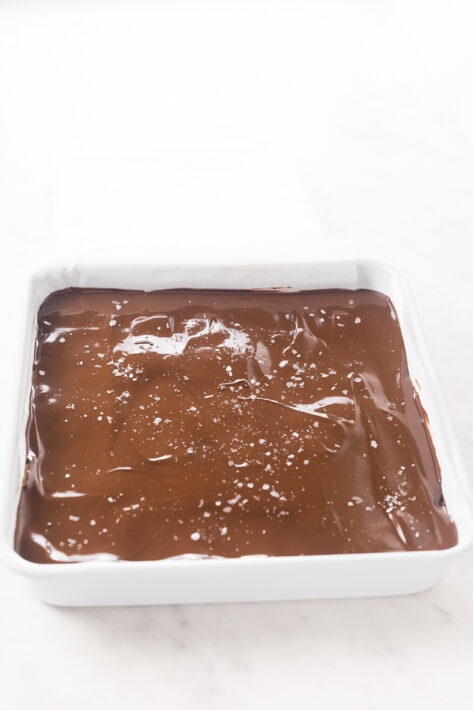 Spread melted peanut chocolate topping, sprinkled with flakey salt, just before freezing the no bake peanut butter bars.
